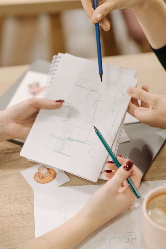 Hands holding pencils and notebook during an artistic brainstorming session.